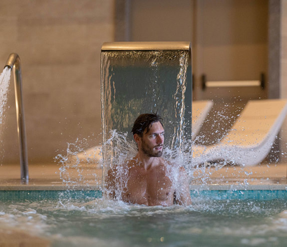 Miraggio visitor under the indoor pool waterfall