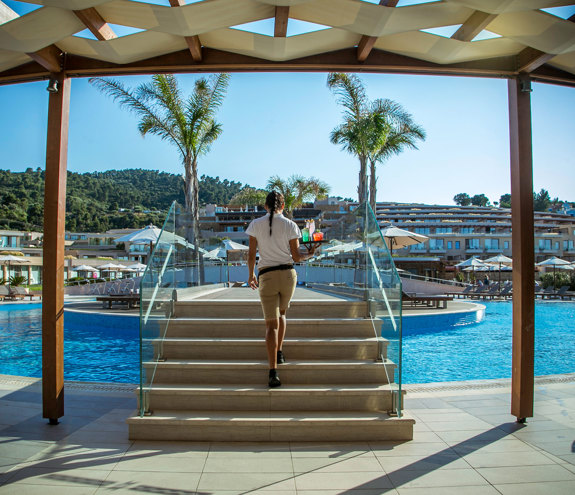 Oasis Pool Bar waitress walking up the pool bridge to serve drinks